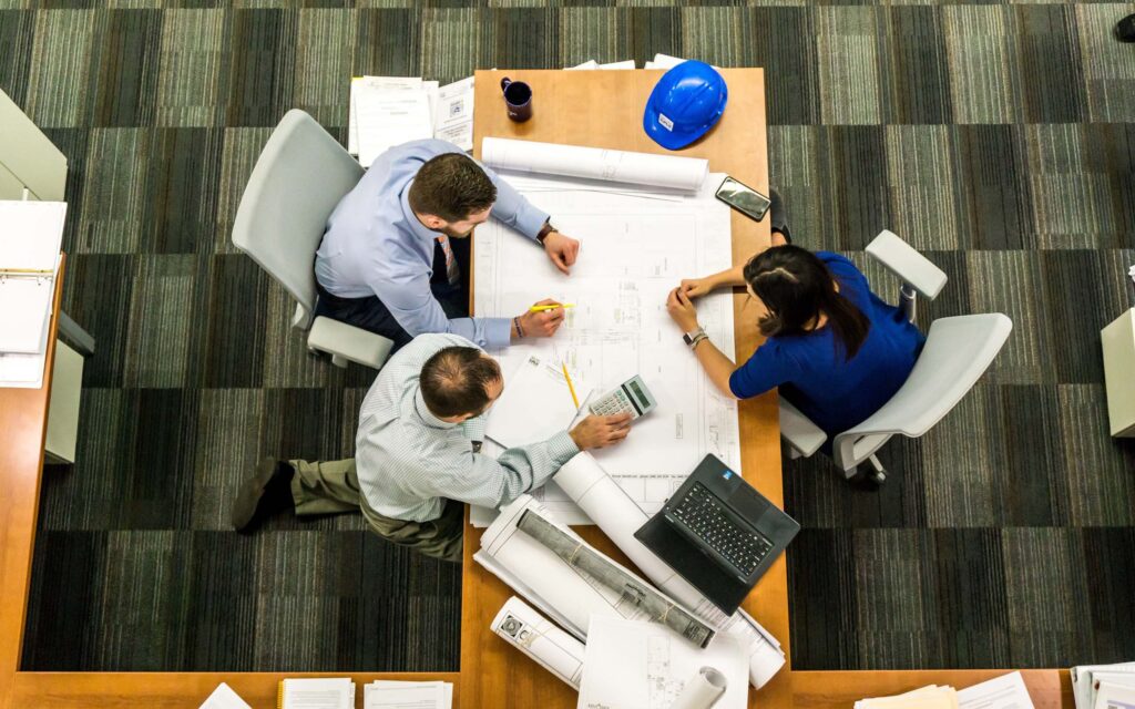 Three business people working on a large piece of paper together